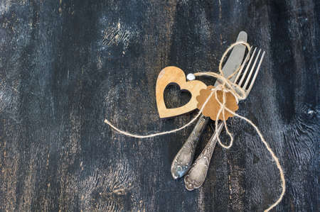 Festive table setting with napkin, vintage silverware and hearts on dark rustic wooden table with copyspaceの写真素材