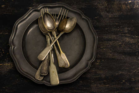 Vintage plate full of vintage silverware on rustic wooden tableの写真素材