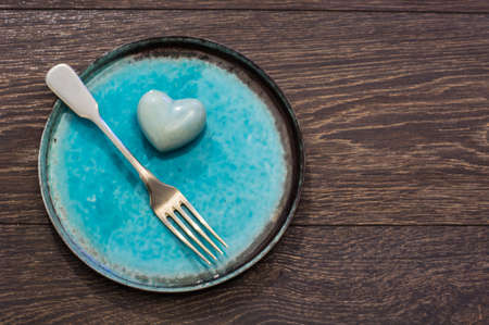 Festive table setting with red rose and heart on rustic wooden table with copyspaceの写真素材