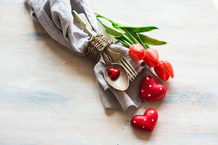 Festive table setting for St. Valentines Day celebration on white rustic wooden table with copyspace