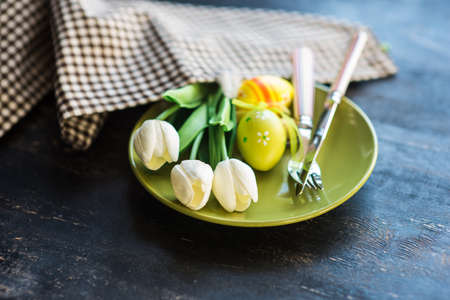 Table setting for Easter dinner with eggs on rustic wooden table
