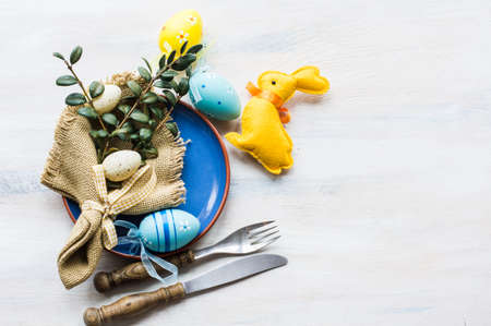 Table setting for Easter dinner with tulips and eggs on rustic wooden tableの写真素材