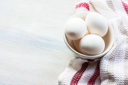 eggs in a porcelain bowl on the rustic wooden tableの写真素材