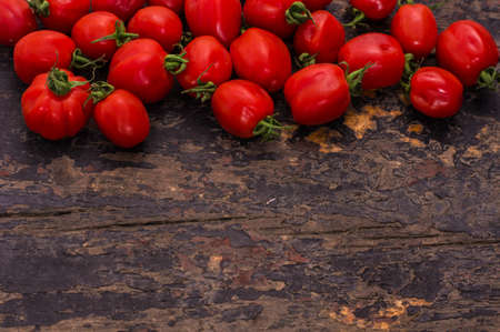 Fresh ripe organic cherry tomatoes and bright ceramic plates on dark wooden table wt copyspaceの写真素材