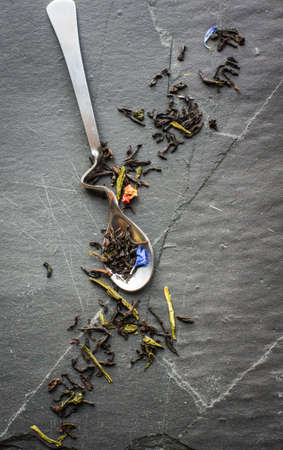 Spoon with floral tea on vintage dark board with copyspaceの写真素材