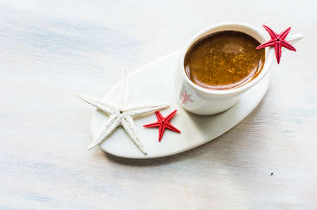 Cup of coffee with sea stars and ship on wooden background with copyspaceの写真素材