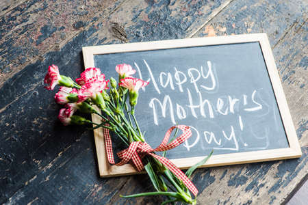 Festive concept with white and red carnation flowers on dark rustic wooden backgroundの写真素材