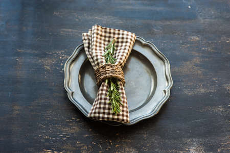 Table setting with fresh rosemary and rustic silverware on dark wooden tableの写真素材
