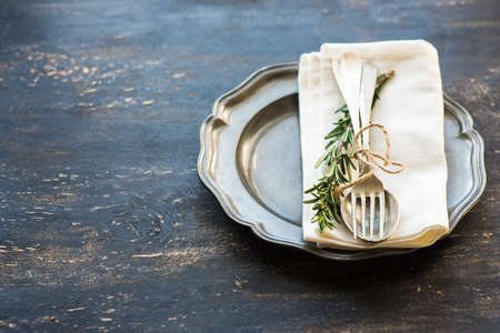 Table setting with fresh rosemary and rustic silverware on dark wooden tableの写真素材