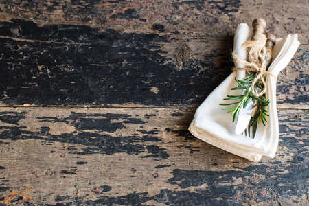 Table setting with fresh rosemary and rustic silverware on dark wooden tableの写真素材