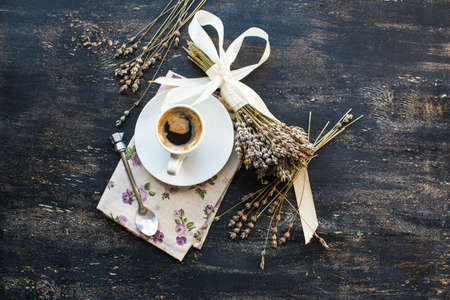Cup of coffee and dried lavender flowers on dark wooden tableの写真素材
