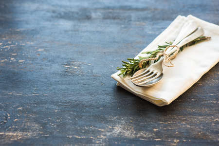 Table setting with fresh rosemary and rustic silverware on dark wooden tableの写真素材