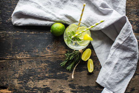 Fresh homemade lemonade with lime, lemon, rosemary and ice on rustic wooden table with copyspaceの写真素材