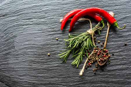 Organic spices on dark stone background - rosemary and different colors peppercornの写真素材