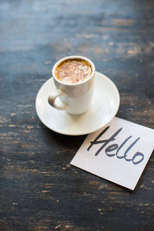 Cup of coffee and Hello note on dark wooden backgroundの写真素材