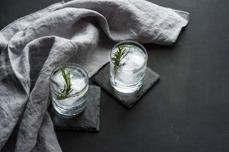 Fresh homemade lemonade with lime, lemon, rosemary and ice on rustic wooden table with copyspace