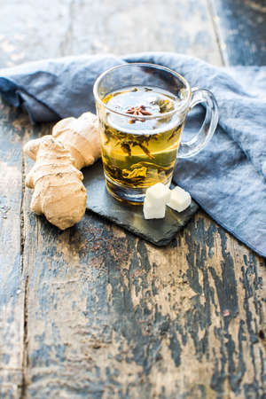 Tea flat lay with ginger, dried tea leaves, honey spoon and sugar on a dark wooden backgroundの写真素材