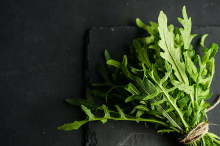 Organic food concept with fresh leaves of ruccola herb on dark backgroundの写真素材