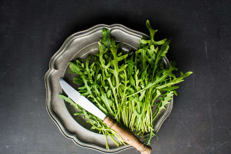 Organic food concept with fresh leaves of ruccola herb on dark backgroundの写真素材