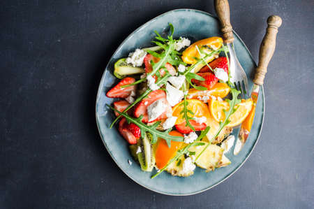Organic fruit dessert with fresh pineapple, kiwi, orange ,strawberries anf rukkola herb