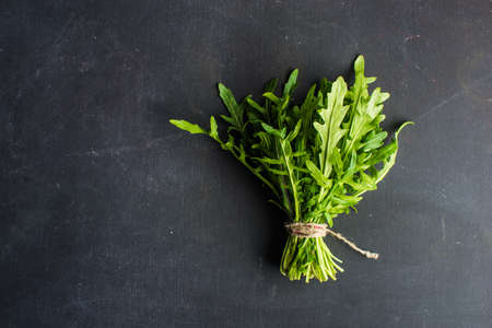 Organic food concept with fresh leaves of ruccola herb on dark backgroundの写真素材