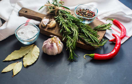 Different spices like a rosemary herb, bay leaf, garlic, pepper and salt on a wooden table as a cooking conceptの写真素材