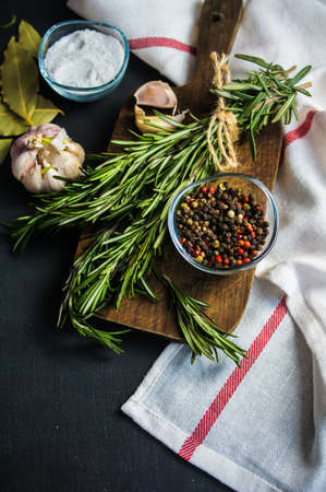 Different spices like a rosemary herb, bay leaf, garlic, pepper and salt on a wooden table as a cooking conceptの写真素材