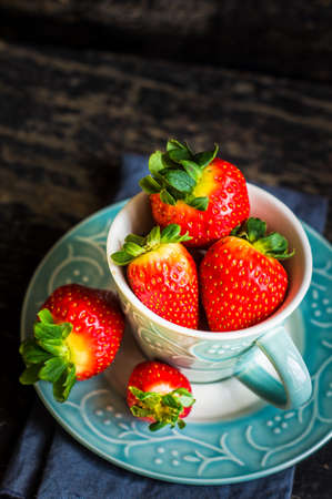 Rustic cup full of fresh strawberries on dark wooden table with copyspaceの写真素材