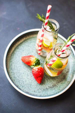Organic fruit detox drink with lime, strawberry and rosemary herb on rustic backgroundの写真素材