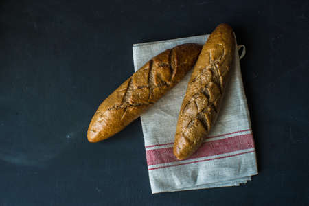 Fresh homemade bread with rustic towel on dark wooden table with copyspace