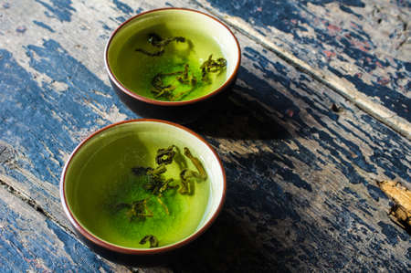 Green tea and leaves on rustic wooden tableの写真素材