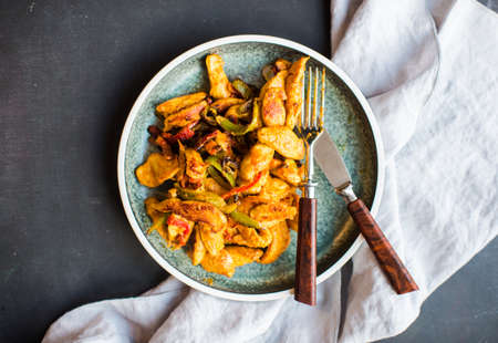 Rustic plate full of chicken in curry with vegetables on dark wooden tableの写真素材
