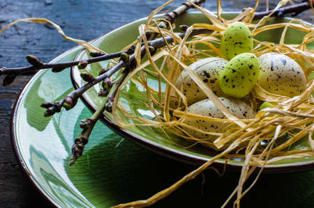 Festive table setting for Easter dinner with bright easter eggs on green platesの写真素材