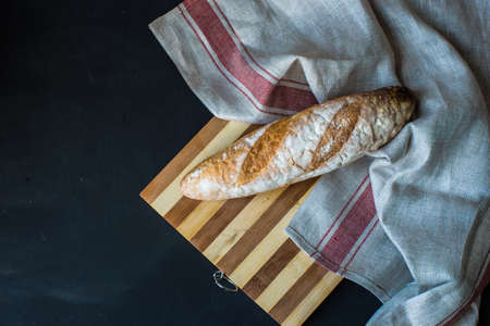 Fresh homemade bread with rustic towel on dark wooden table with copyspaceの写真素材