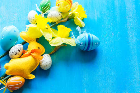 Festive easter frame with yellow daffodils and easter eggs on bright blue wooden backgroundの写真素材
