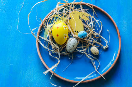 Festive table setting for Easter dinner with bright easter eggs and yellow daffodilsの写真素材