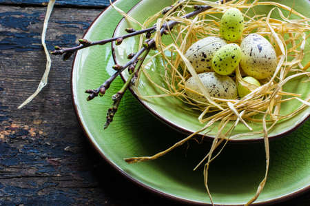 Festive table setting for Easter dinner with bright easter eggs on green platesの写真素材