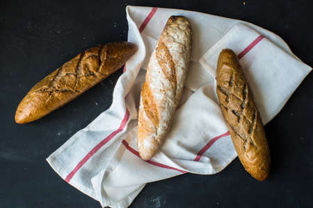Fresh homemade bread with rustic towel on dark wooden table with copyspaceの写真素材