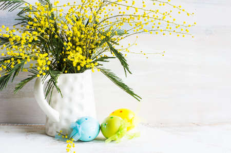 Easter festive frame with bright yellow mimosa (acacia) flowers and easter eggs a on wooden backgroundの写真素材