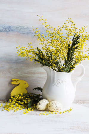 Easter festive frame with bright yellow mimosa (acacia) flowers and easter eggs a on wooden backgroundの写真素材