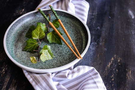 Rustic table setting with wild grape leaves on the plate on dark wooden tableの写真素材