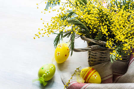 Easter festive frame with bright yellow mimosa (acacia) flowers and easter eggs a on wooden backgroundの写真素材