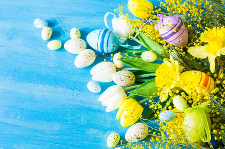 Easter festive frame with bright yellow mimosa (acacia) flowers and easter eggs a on wooden backgroundの写真素材