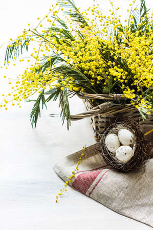 Easter festive frame with bright yellow mimosa (acacia) flowers and easter eggs a on wooden backgroundの写真素材