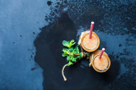 Healthy food concept with organic citrus smoothie of grapefruit, lemon, mint and banana on dark wooden table with copyspaceの写真素材