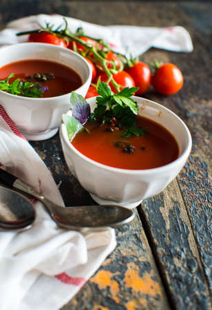 Gazpacho tomato soup and ingredients on dark wooden table