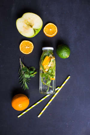 Organic food concept with bottle of healthy drink with lime, lemon and mint and water on rustic wooden table with copyspaceの写真素材