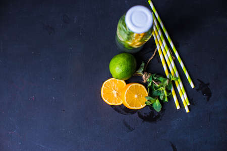 Organic food concept with bottle of healthy drink with lime, lemon and mint and water on rustic...