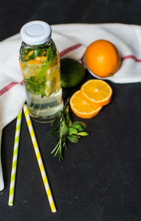Organic food concept with bottle of healthy drink with lime, lemon and mint and water on rustic...