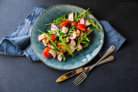Spring healthy salald with fresh organic tomatoes, radish and rukkola herb on rustic plate with...
